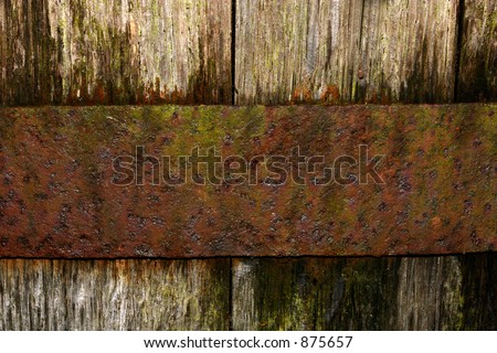 A section of an old oak whisky barrel, with a rusty band of metal holding the oak boards in place.