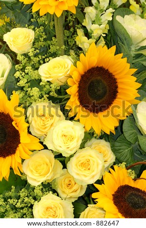 An arrangement in yellow, of sunflowers, roses, antirrhinums and ladies mantle.