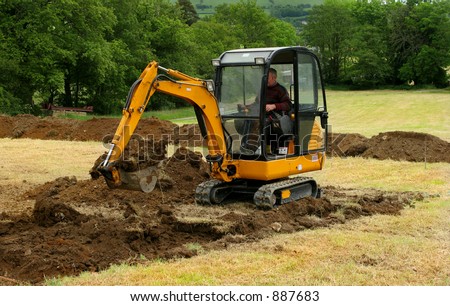 A man operating a mini digger in a field.