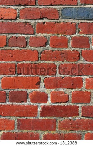 Old red brick wall with one odd blue brick.