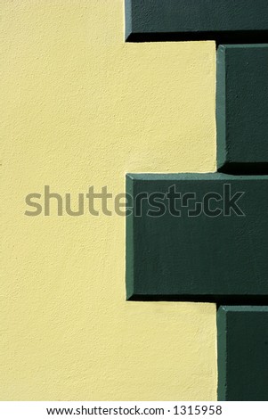 Section of cream painted render with green painted stone detailing on a building.