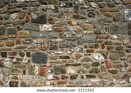 Old stone wall with varying sizes , shapes and colored stones.
