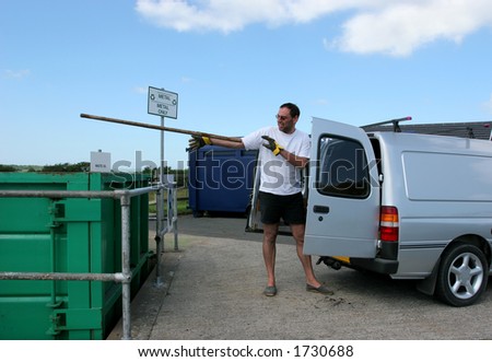 Man throwing metal waste into a metal recycling container and standing next to a van at a disposal center.