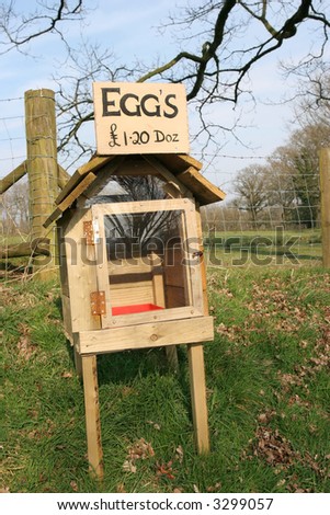 Rough wooden and perspex honesty egg box in rural countryside with eggs for sale sign. Honesty egg boxes are used in rural communities where buyers leave payment in the box in exchange for eggs.