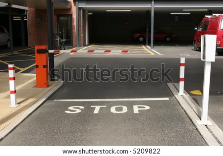 Entrance to an underground car park with gated barrier and entry machine.