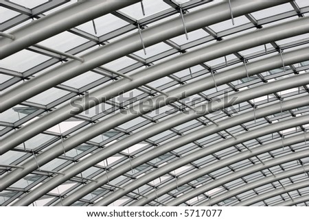 Section of the curved reinforced steel roof joists in a conservatory with glass panes in between.