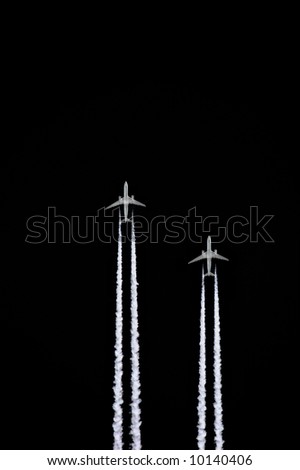 Two jet aircraft flying in a vertical parallel formation with smoke trails, set against a black sky background.