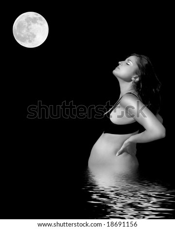 Pregnant woman wearing a bra with reflection over rippled water and full moon over black background.
