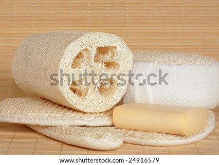 Natural skincare cleansing beauty products including, sisal pad,sponge and exfoliating glove with loofah and natural soap. Over bamboo mat background.