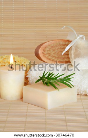 Natural skincare cleansing products lit by a candle and set against a bamboo background.