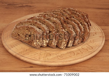 Soda bread loaf in slices on a carved wooden beech bread board over oak wood. Mass produced bread board.