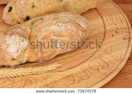 Olive bread on a beech wood board with wheat.  Mass produced bread board.