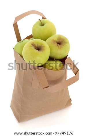 Golden delicious apple fruit in a brown paper recycled carrier bag isolated over white background.