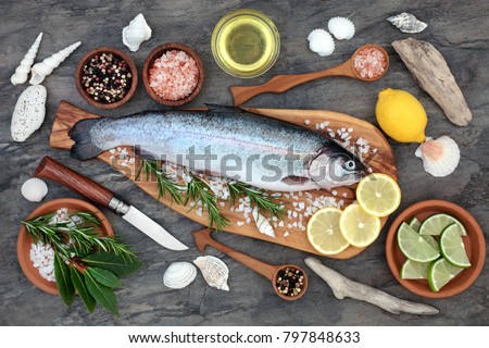 Rainbow trout health food on an olive wood board with seasoning. Very high in omega 3 fatty acid and beneficial to maintain a healthy heart.