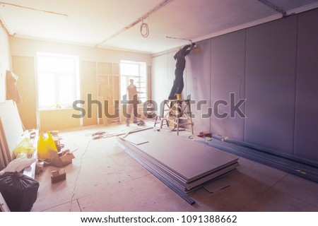 Workers are installing plasterboard (drywall) for gypsum walls in apartment is under construction, remodeling, renovation, extension, restoration and reconstruction.