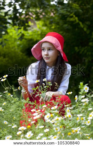 Sweet little girl in the rose garden.She picks oil rose for aroma therapy or perfumes