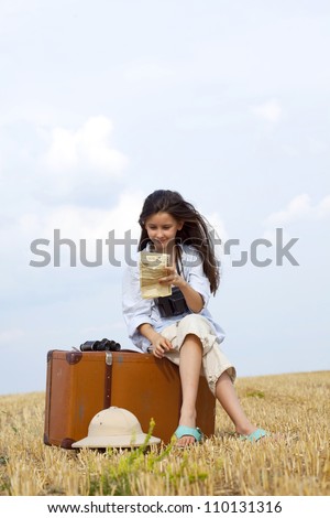 Sweet little traveler on the field with suitcase , old camera and binocular