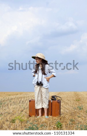 Sweet little traveler on the field with suitcase , old camera and binocular