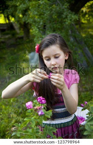 Sweet little girl picks oil aroma roses in the garden