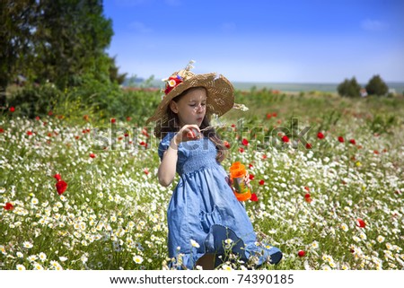 Sweet little girl pick a flowers in a wild meadow with poppies and daisies,