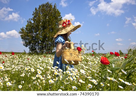 Sweet little girl pick a flowers in a wild meadow with poppies and daisies,