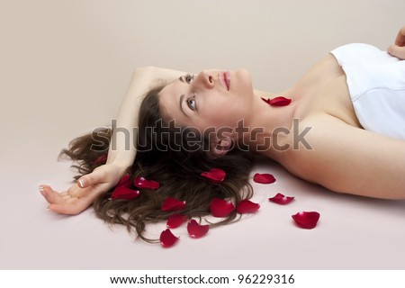 Beautiful young girl on the simple background with rose leafs