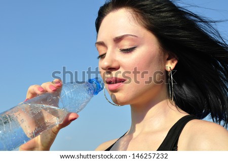thirsty young woman drinking cold water in hot day