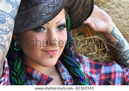 young tattooed stylish woman with dreadlocks in cowgirl style
