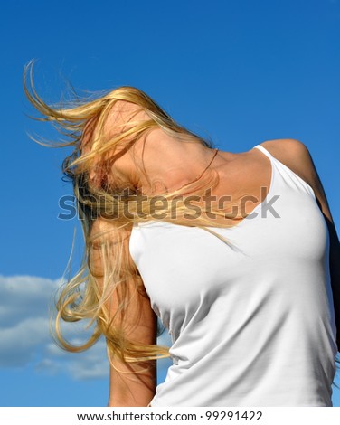 young beautiful woman against blue sky background, in low angle view