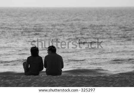 couple in beach watching the sea in black and white