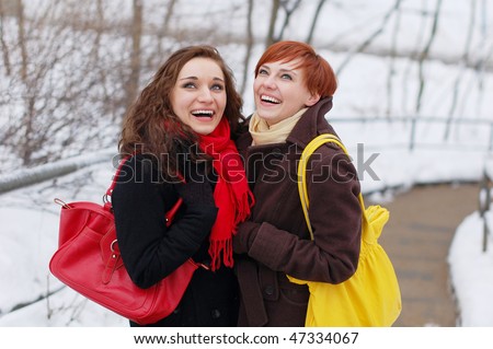 Two girlfriends laughing cheerfully on a snowy day.