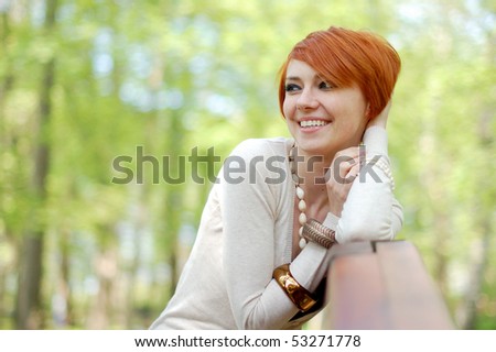 Beautiful woman smiling to the side of the photograph; standing outdoor on a sunny day