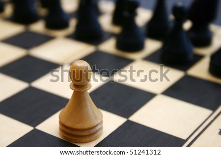 Wood chess game shows white brave pawn challenge stronger enemy.
