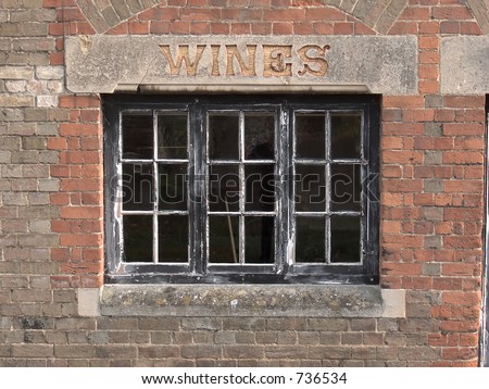 Window with \'Wines\' carved in stone lintel of old Wines and Spirits shop with brick background