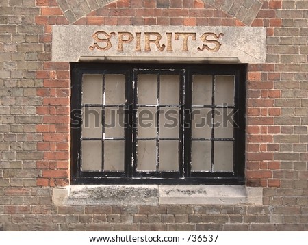 Window with \'Spirits\' carved in stone lintel of old Wines and Spirits shop with brick background