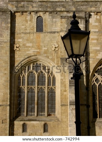 Gothic window and old lamp in morning sun, Winchester cathedral England