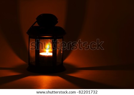 Lantern with alight candle in the dark