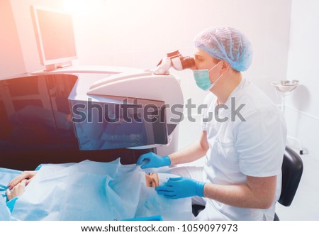Laser vision correction. Surgeon in the operating room during ophthalmic surgery. Eyelid speculum. Lasik treatment. Patient under sterile cover