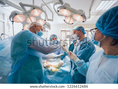 Process of trauma surgery operation. Group of surgeons in operating room with surgery equipment. Medical background