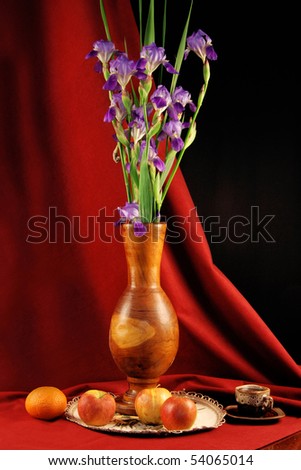 Still life, wooden vase with flowers and fruits on red background
