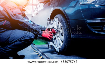 Car mechanic installing sensor during suspension adjustment. Wheel alignment work at repair service station