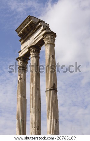 Three roman columns against a blue sky with clouds