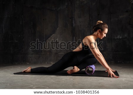 Fitness woman doing stretching, warming up, pilates exercises using foam roller