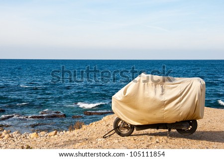 covered motorbike parked on the beach