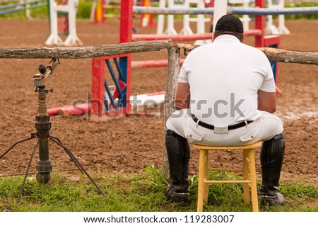 lonely jockey looking at the empty field with hurdles