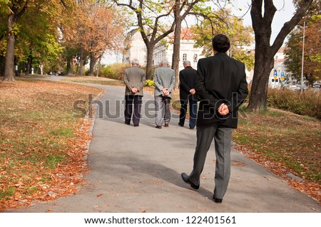 age difference, young man in the suit walking behind seniors,with both hands on his back,thinking about ,passing of life time