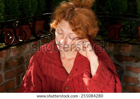 freckled woman wiping her tears against brick wall