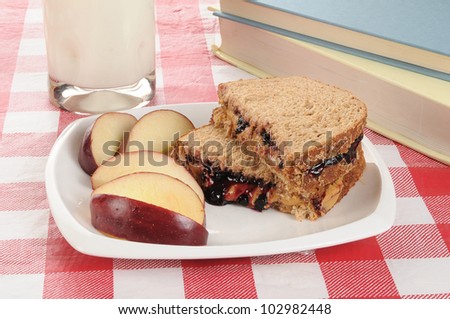 Peanut butter and jelly sandwich with an apple and school text books