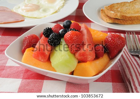 A bowl of fruit salad with melon slices and berries