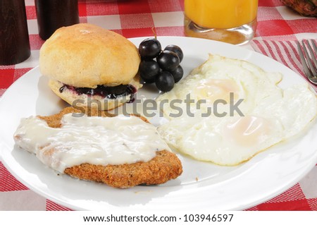 A country or chicken fried steak with fried eggs and a biscuit
